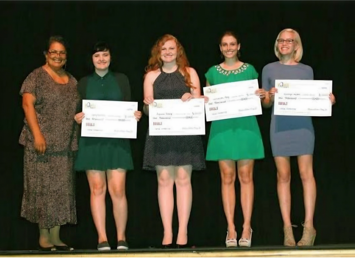 Scholarship recipients holding award checks on stage